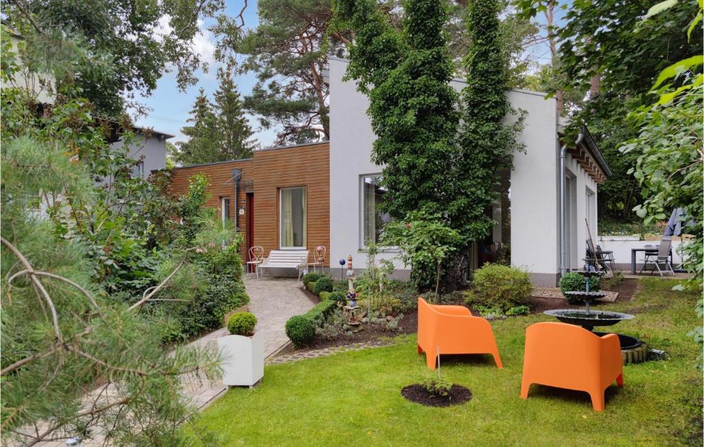 einen Garten mit orangefarbenen Stühlen und ein Haus in der Unterkunft Beautiful Home In Seebad Lubmin With Wifi And 3 Bedrooms in Lubmin