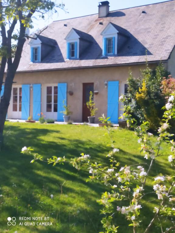 uma casa com portas azuis num relvado verde em La case 