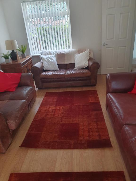 a living room with a leather couch and a rug at Quiet house 8 mins from NEC/AIRPORT in Marston Green