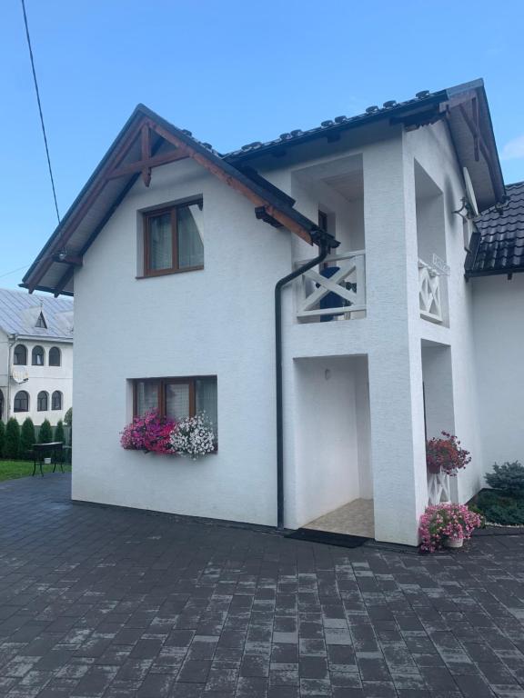 Casa blanca con 2 ventanas y flores en Котедж Зґарда en Yaremche