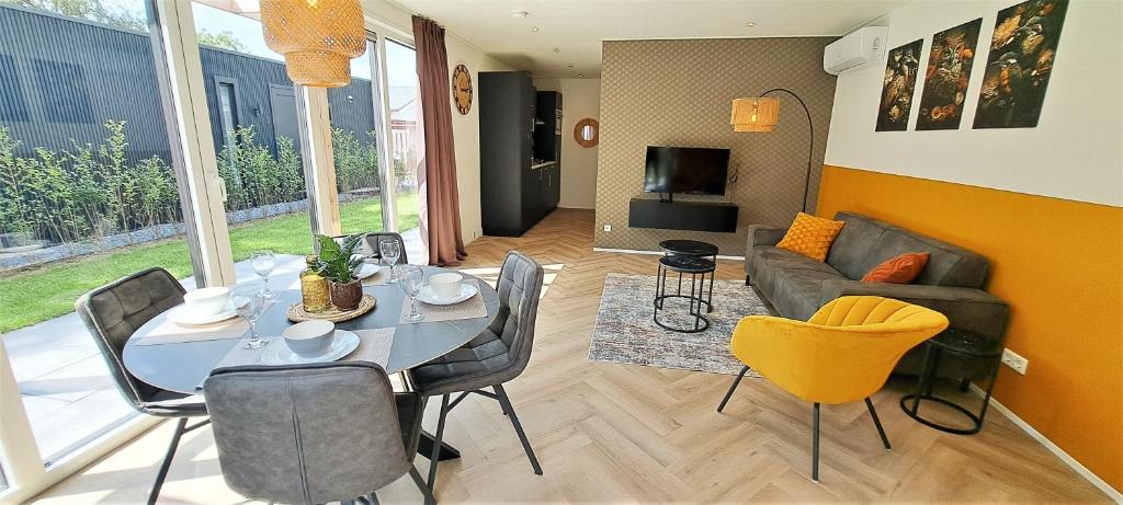 een woonkamer met een tafel en stoelen en een bank bij Veluwe Home 'De Bosvogel' luxe natuurhuis in Ermelo