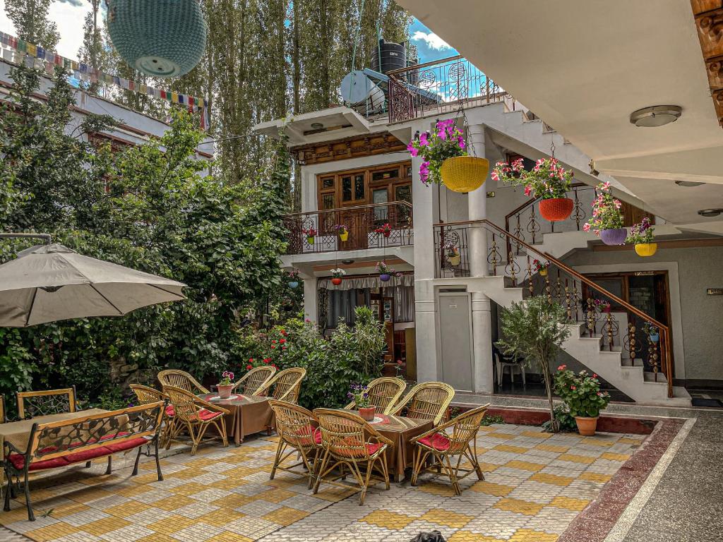 un patio con sillas, mesas y una sombrilla en Hotel shaynam en Leh