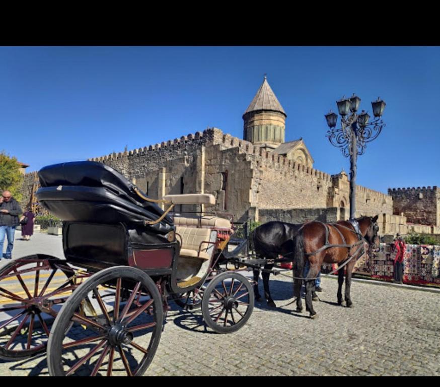 un carruaje tirado por caballos frente a un castillo en Hotel bereka, en Mtskheta