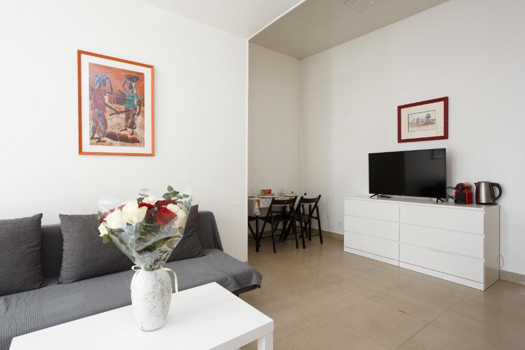 een woonkamer met een bank en een tv bij LE BLANC CENTRE F2 in Le Blanc-Mesnil