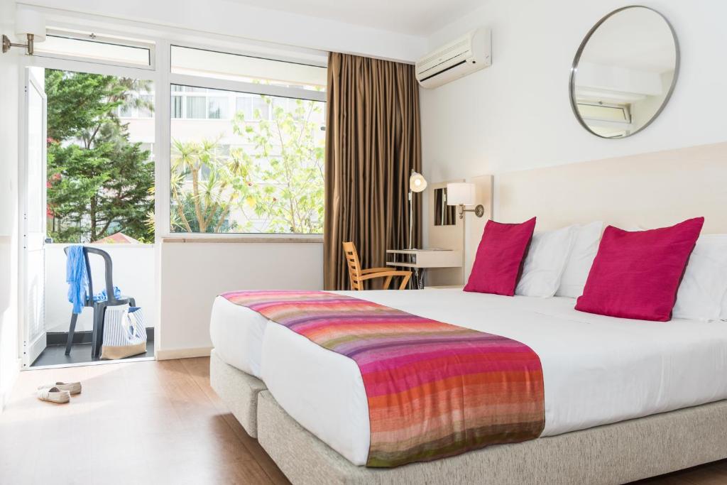 a hotel room with a large bed with red pillows at Hotel Londres Estoril / Cascais in Estoril