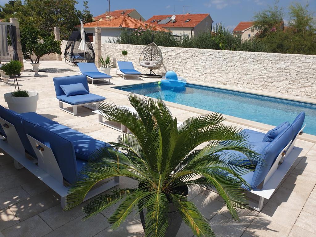 a pool with blue chairs and a palm tree next to it at Villa Sarah in Supetar