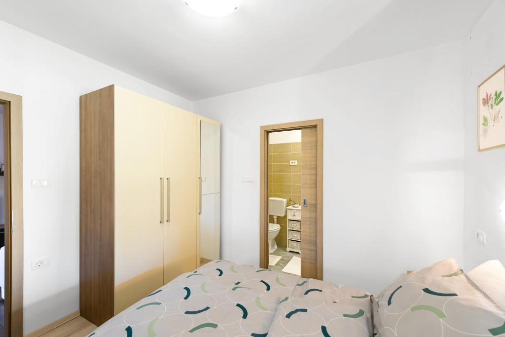 a white bedroom with a bed and a mirror at Apartment Ivana in Roč