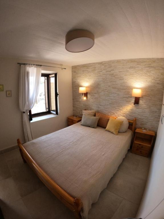 a bedroom with a large bed and a brick wall at Evi's House in Kandia