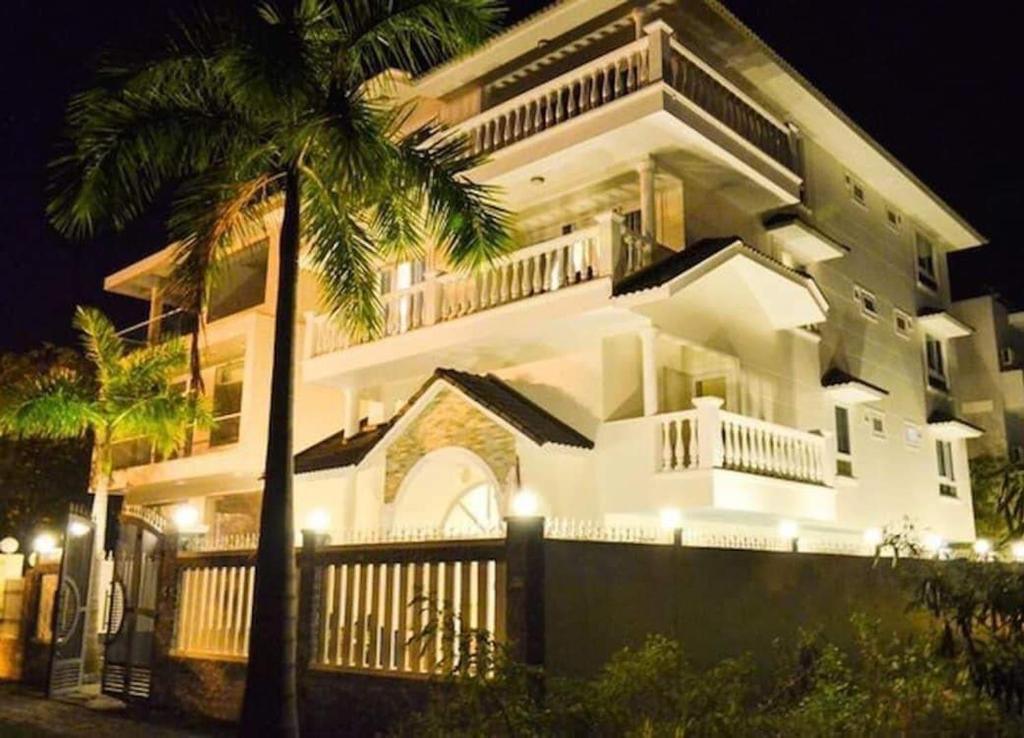 un gran edificio blanco con una palmera delante en Natural An Viên Villa, en Nha Trang