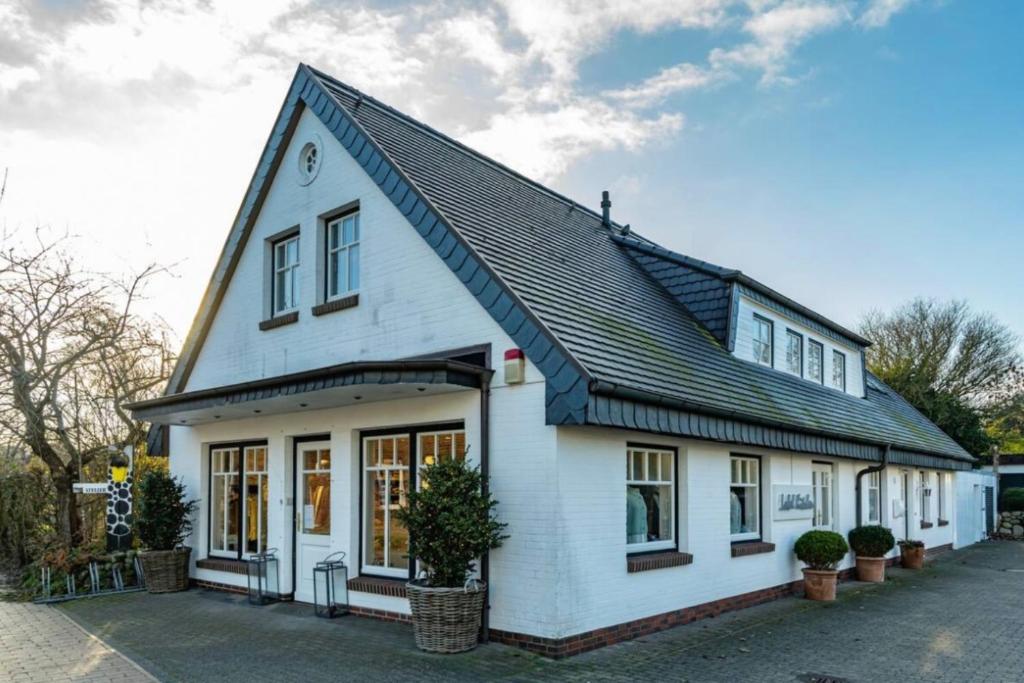 una casa blanca con techo negro en Feriendorf Sylt Deutschland en Tinnum