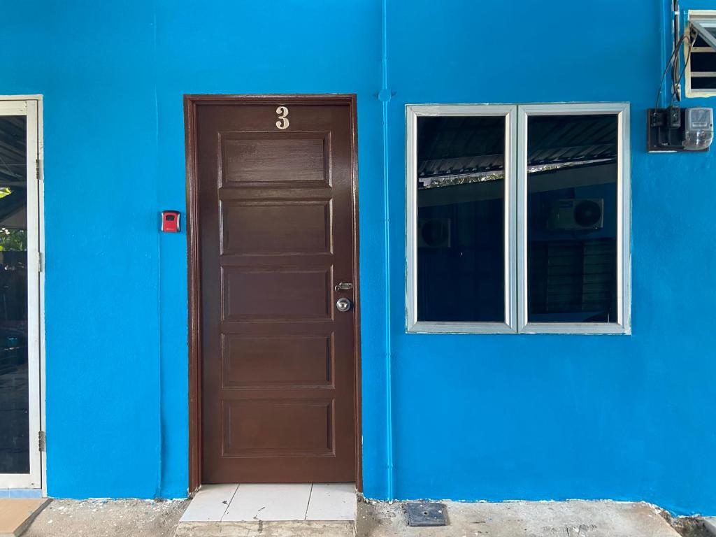 a blue building with a brown door and two windows at Padang Besar Roomstay Firdaus in Padang Besar