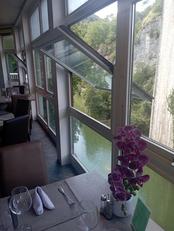 a table with a vase of flowers on a table with a window at hotel restaurant le saint nazaire in Saint-Nazaire-en-Royans