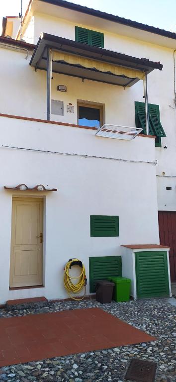 een wit gebouw met groene ramen en een slang bij Bilocale La Tezia in Marciana Marina
