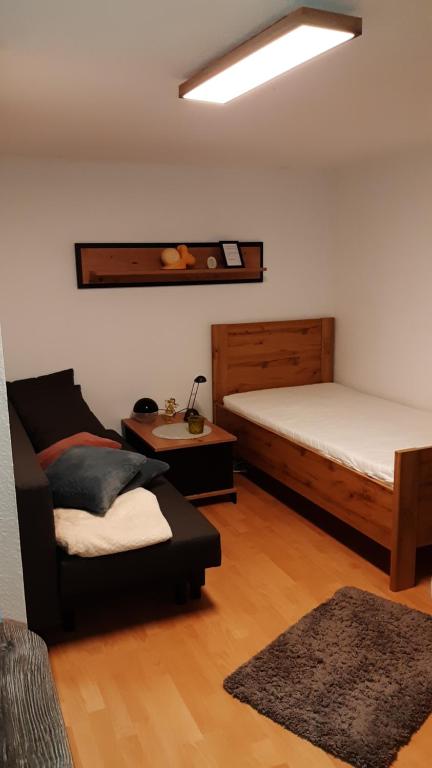een kamer met 2 bedden, een stoel en een bank bij Appartement am Rondell in Hösbach