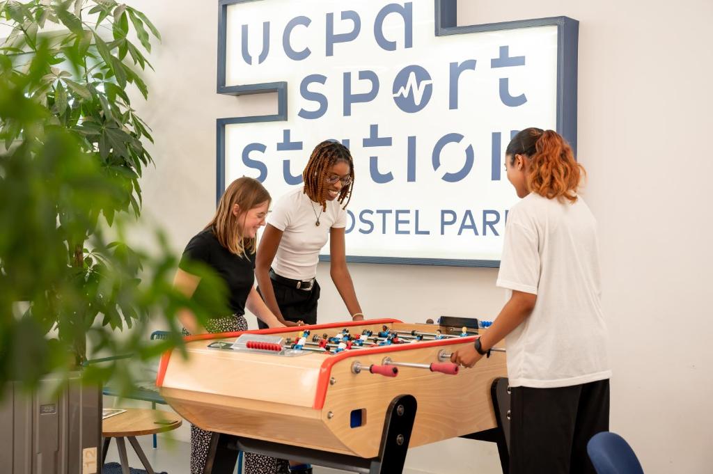 un grupo de personas de pie alrededor de una mesa con un vertisementosateosateosatélitesatélites en UCPA SPORT STATION HOSTEL PARIS, en París