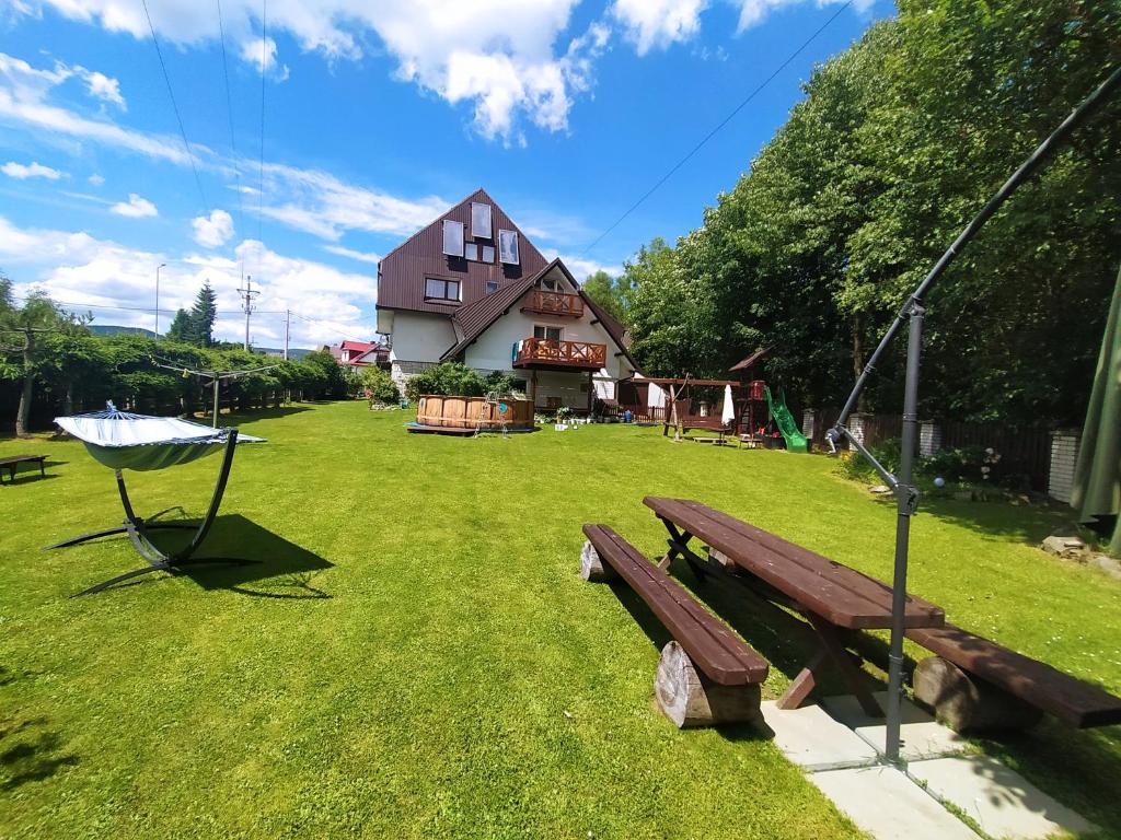 a wooden bench in a yard with a house at Noclegi u Kowalczykow in Zubrzyca Górna