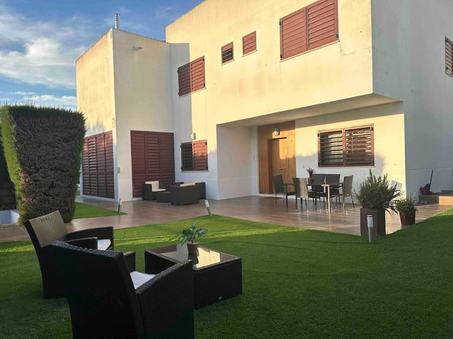 uma casa com um relvado com cadeiras e uma mesa em Modern 5-bedroom villa with pool em Montequinto