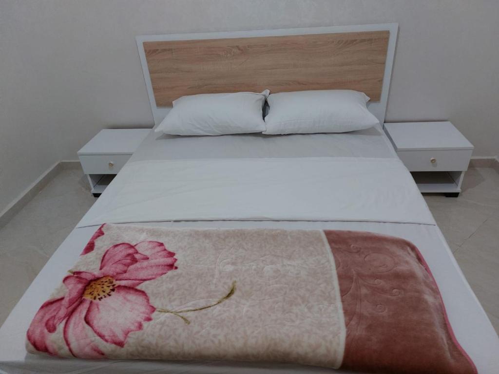 ein Schlafzimmer mit einem Bett mit einer Blume darauf in der Unterkunft RESIDANCE ESSALAM in El Aaiún