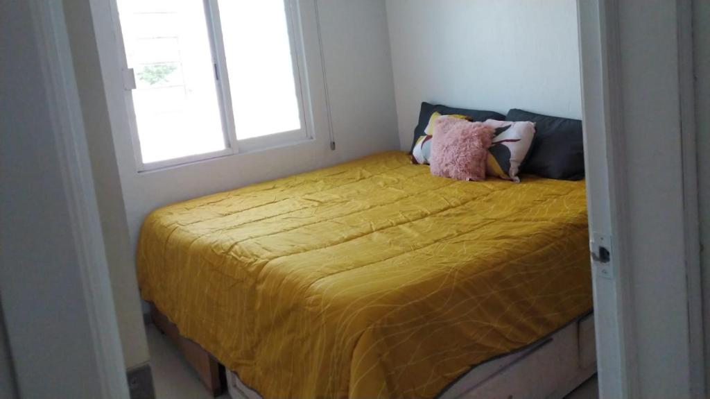 - une chambre dotée d'un lit jaune avec un animal rembourré dans l'établissement HABITACION COMODA, à Guadalajara