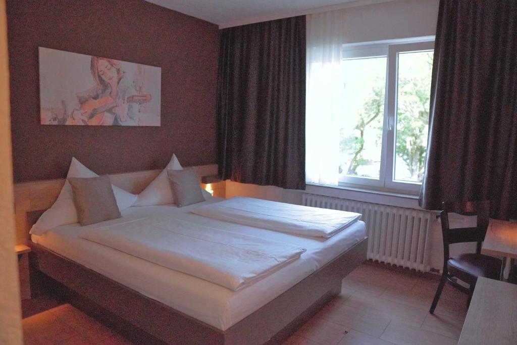 Schlafzimmer mit einem großen weißen Bett vor einem Fenster in der Unterkunft Hotel Frohnhauser Hof in Essen