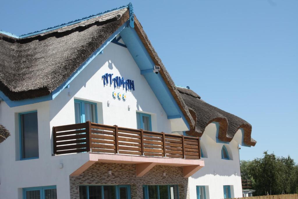 a house with a thatched roof and a balcony at Pensiunea Ataman in Murighiol