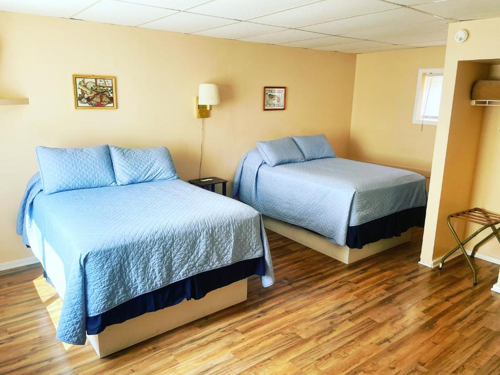Cette chambre comprend 2 lits avec des draps bleus et du parquet. dans l'établissement Riverview Inn, à Grayling
