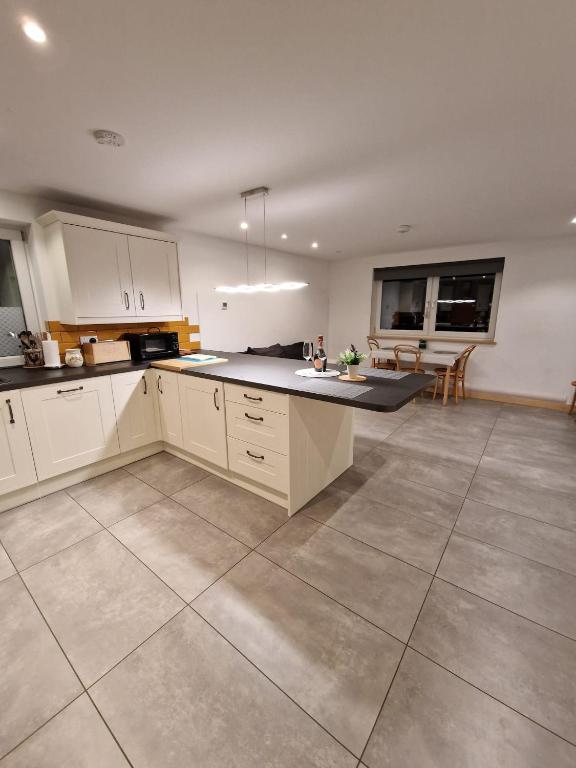 a kitchen with white cabinets and a table in it at Modern two bedroom house in Ormiston