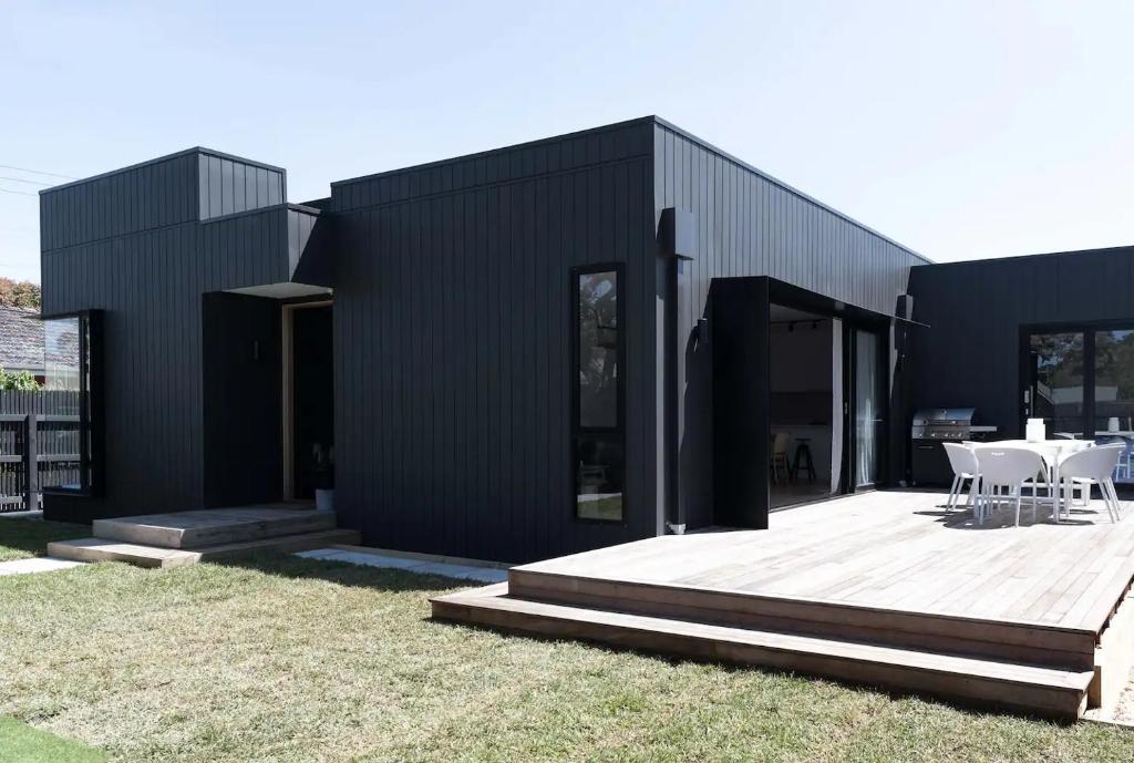 a black house with a wooden deck in front of it at Matilda Rose - BYO LINEN AND TOWELS in Rosebud