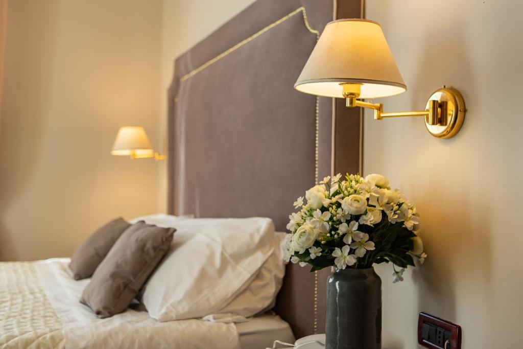 a vase of flowers on a table next to a bed at Hotel Viscardo in Forte dei Marmi