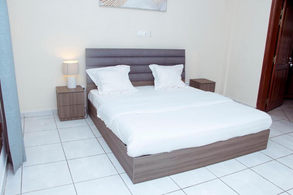 sypialnia z dużym łóżkiem z białą pościelą w obiekcie Résidence Vedette w mieście Jaunde