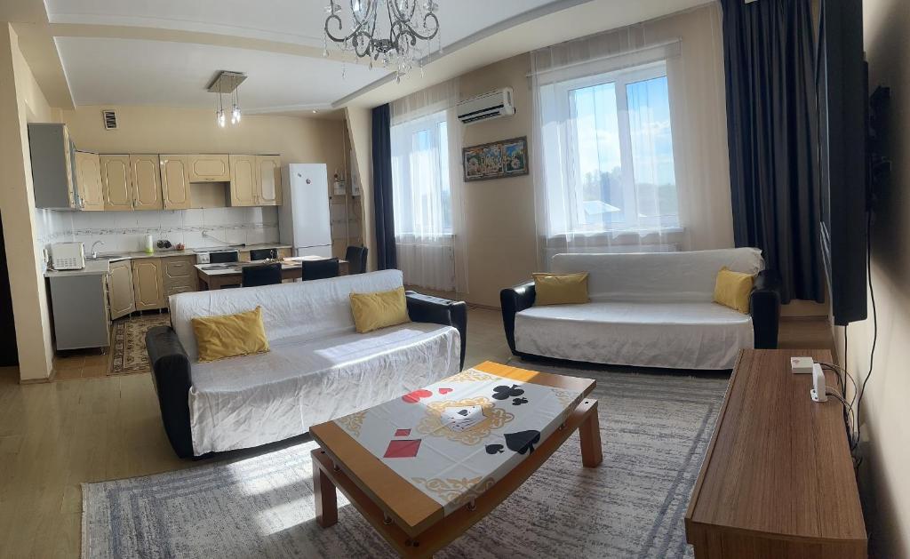 een woonkamer met 2 banken en een tafel bij Просторная и уютная 3х комнатная в центре! in Oral