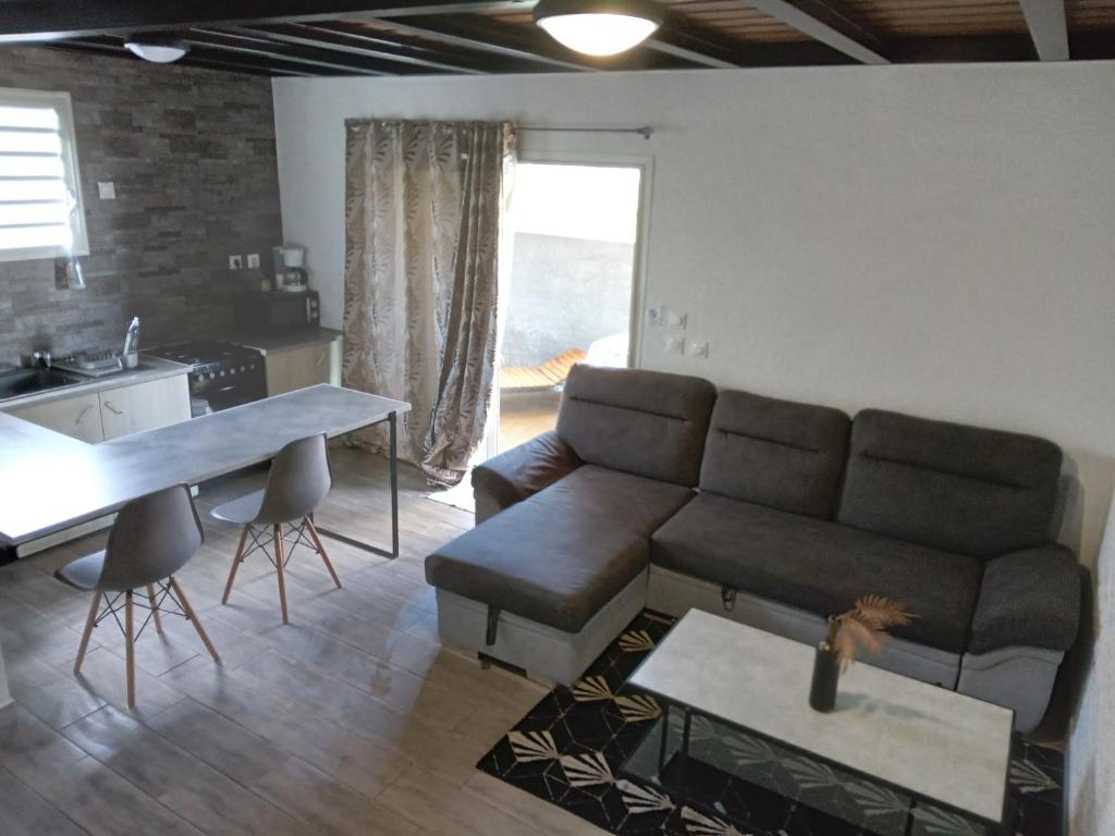 a living room with a couch and a table at aux 4 saisons maison l'opaline in Le Tampon