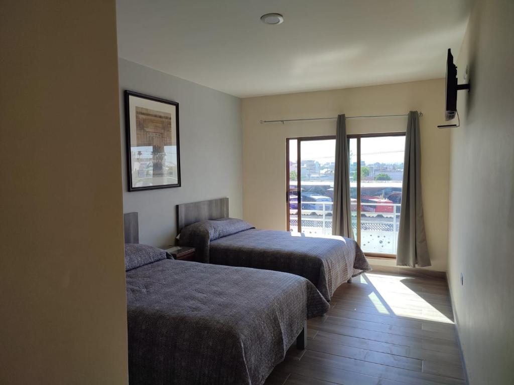 ein Hotelzimmer mit 2 Betten und einem Balkon in der Unterkunft Hotel Posada California in Aguascalientes
