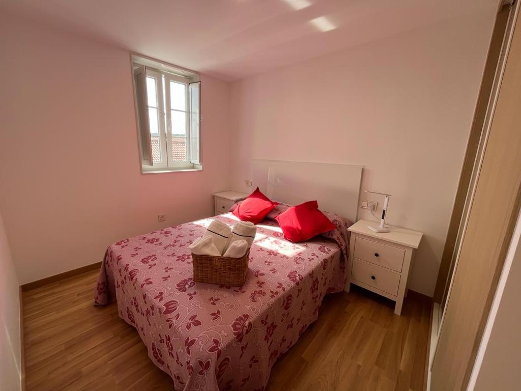 a bedroom with a bed with red pillows and a basket on it at Apartamento Gallaecia Lux in Santiago de Compostela