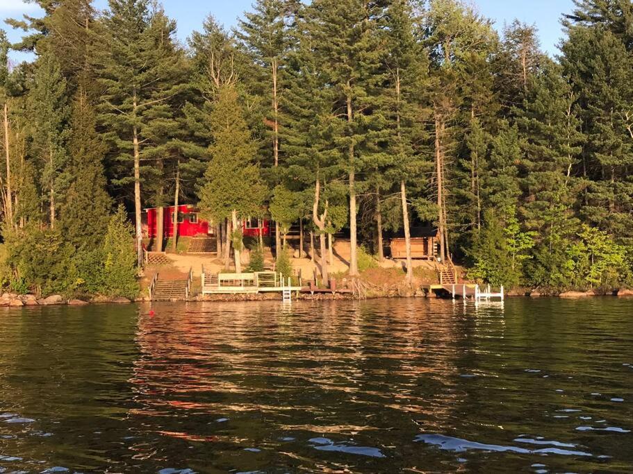 vistas a un lago con una casa y árboles en Well-appointed ADK cabin directly on 106’ water!, 