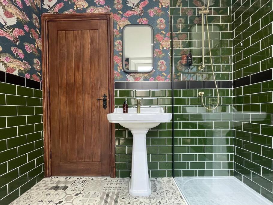 a bathroom with a sink and green tiled walls at The Secret Nook in Maryport
