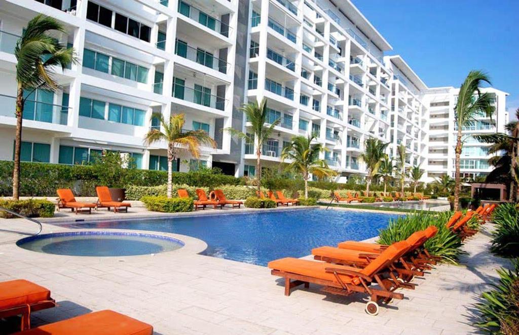 a hotel with a pool and chairs and a building at Morros Suites Apartamentos in Cartagena de Indias