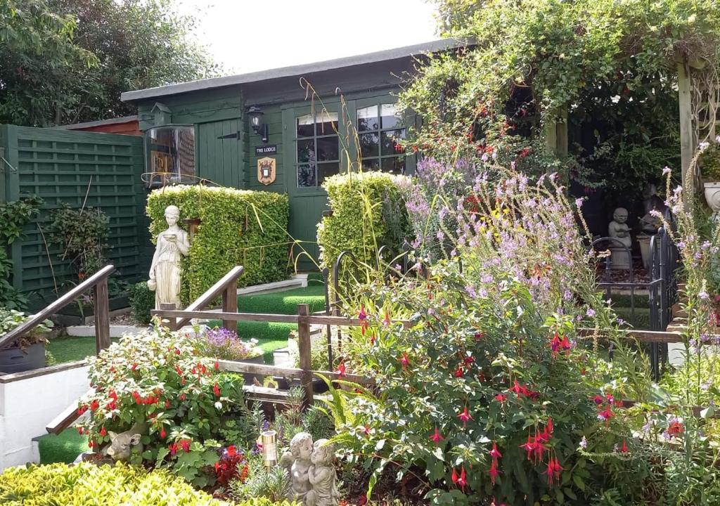 a garden with flowers and a statue in front of a building at Forget-me-not Bungalow in Seaton