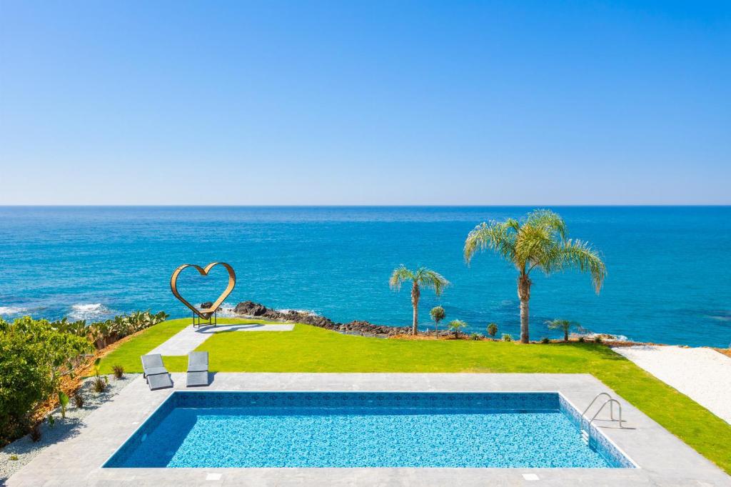 a swimming pool with the ocean in the background at Villa Beach Heaven in Pomos
