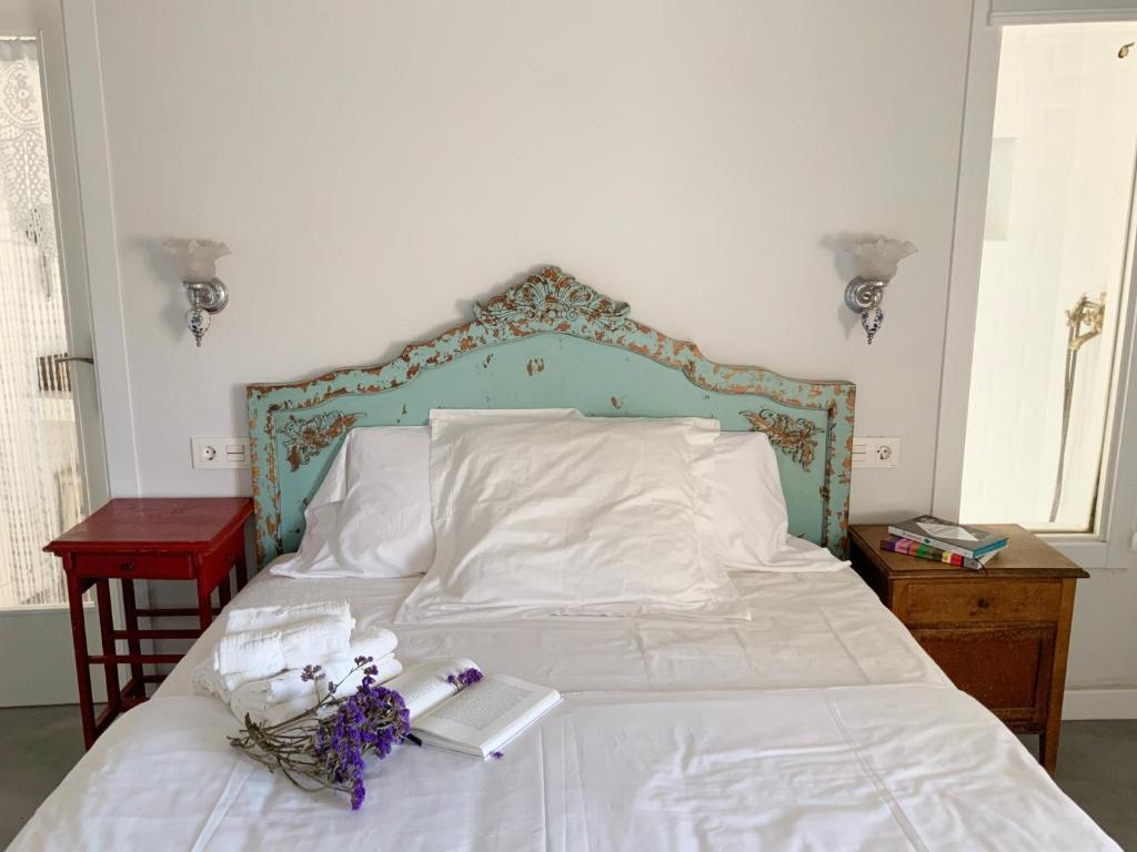 Una cama blanca con un cabecero azul y flores. en La Grulla Dorada, en Perales del Puerto