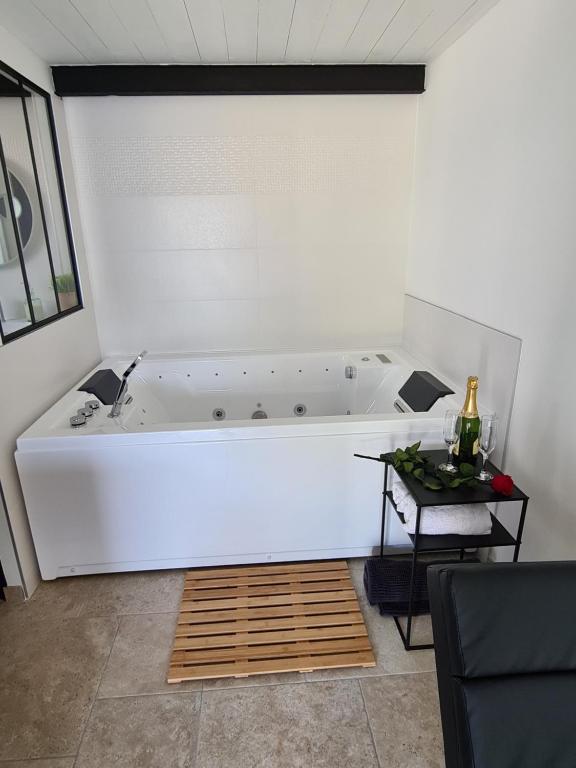 a white bath tub in a room with a table at Gîte spa la parenthèse in Sauve