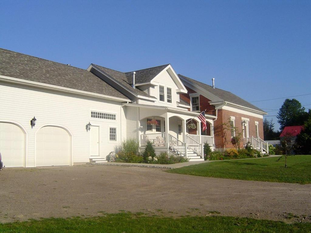 een groot wit huis met een vlag erop bij Dodds Brick House Bed & Breakfast in North Hero