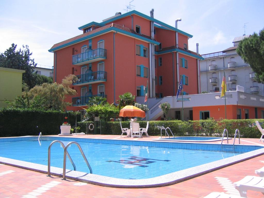 un hotel con piscina frente a un edificio en Hotel Altinate, en Lido di Jesolo