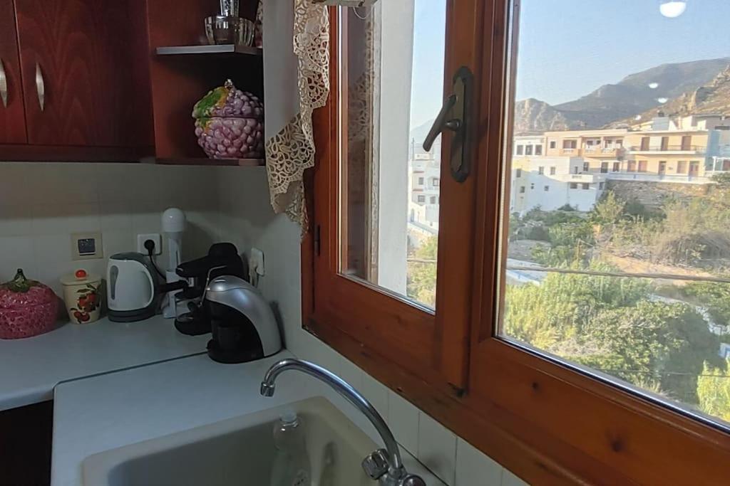 encimera de cocina con fregadero y ventana en Nikitas Luxury House, en Karpathos