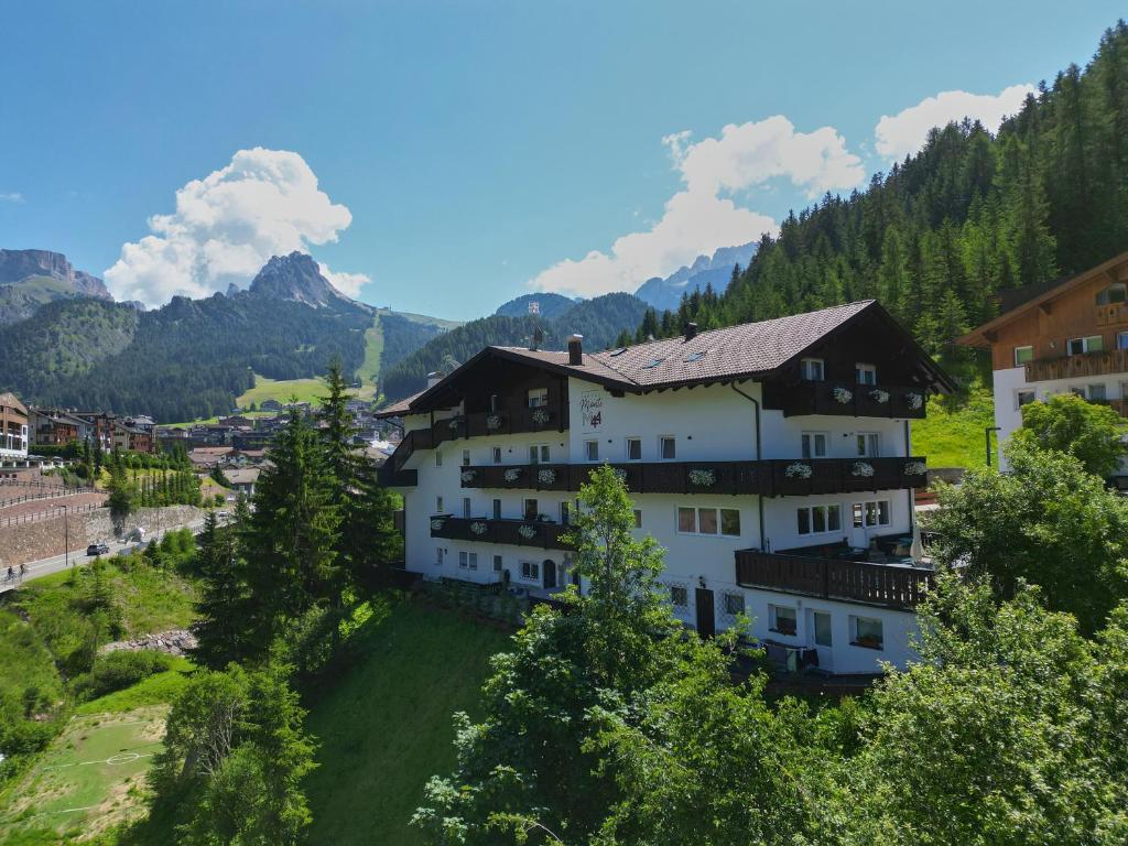 duży biały budynek na wzgórzu z drzewami w obiekcie Hotel Monte44 w mieście Selva di Val Gardena