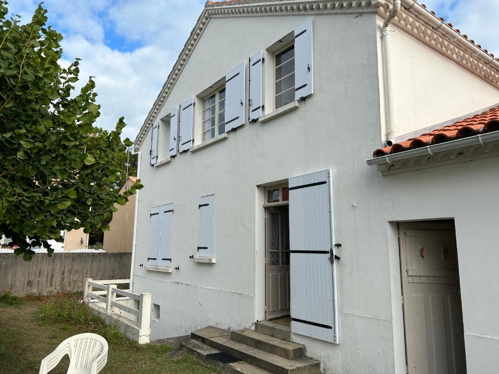 une maison blanche avec des fenêtres blanches et une chaise blanche dans l'établissement La plaisance tilleul, à Notre-Dame-de-Monts