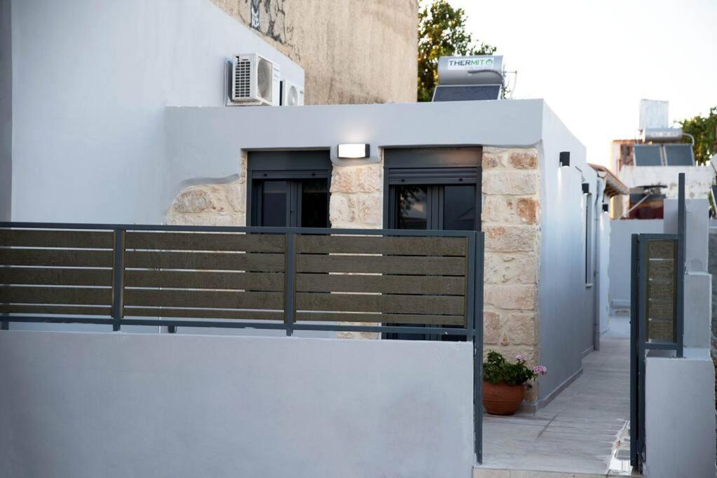 a white building with a black railing on a balcony at Myra city House in Chania