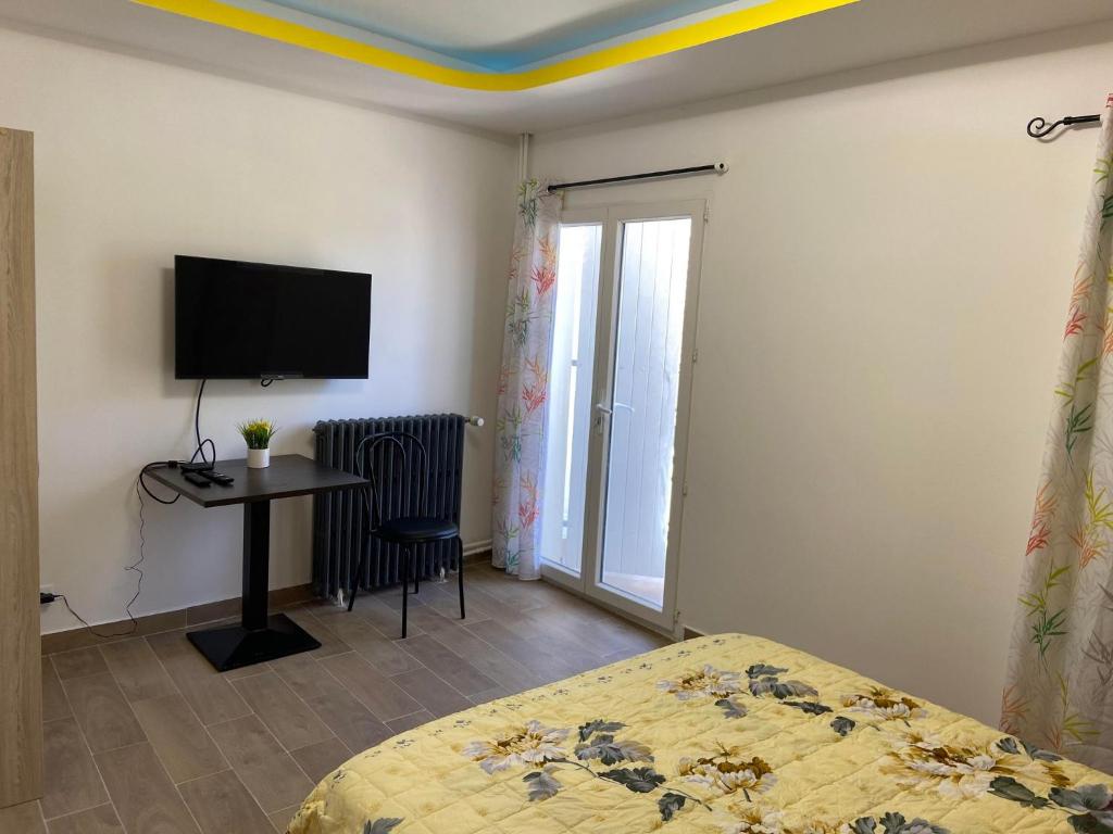 a bedroom with a bed and a desk and a tv at Chambres n°4 (1-2pers) + Balcon in Prayssac