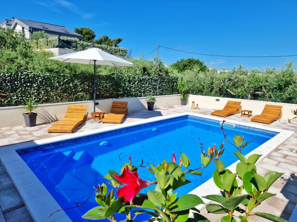 a swimming pool with chairs and an umbrella in a backyard at Casa Bella in Split