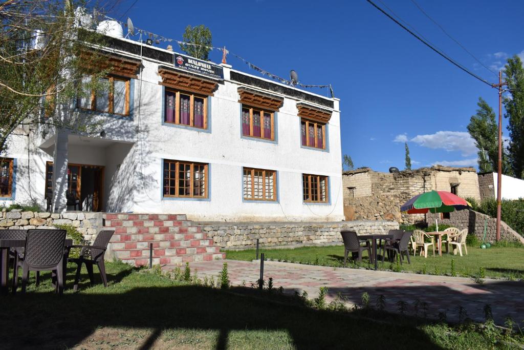 a white building with tables and chairs in front of it at Kushu Guest House in Leh